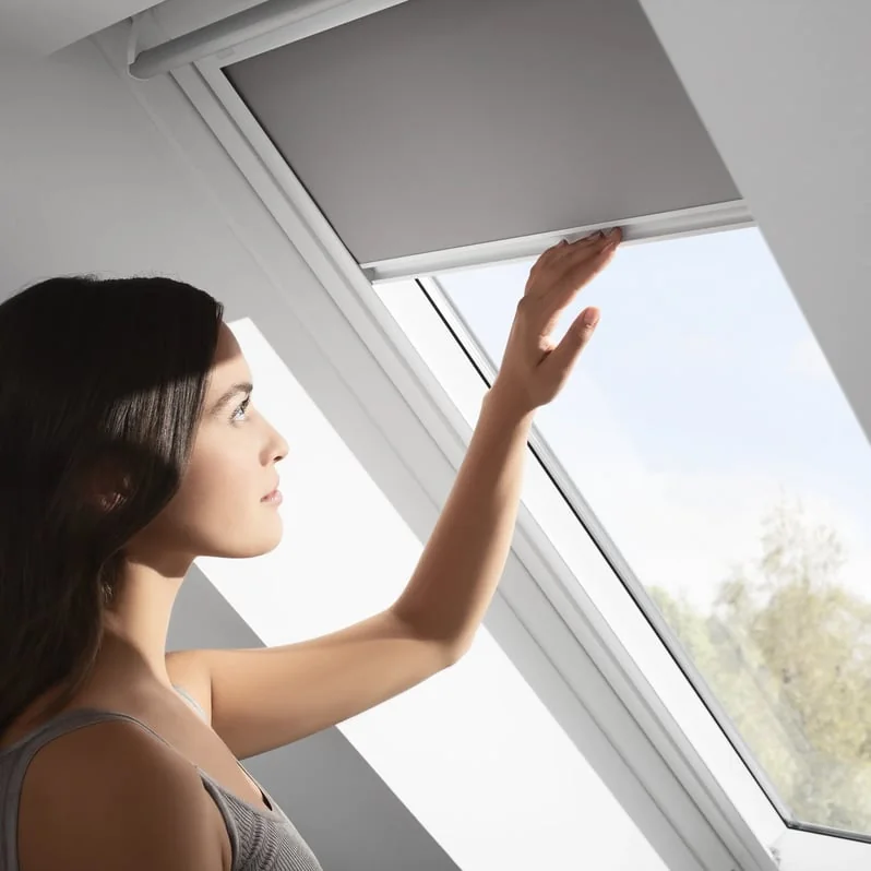 Persona operando a mano la cortina retr&aacute;ctil de una ventana de techo
